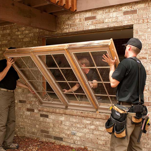 Photo of window installers removing old windows. New window replacement.