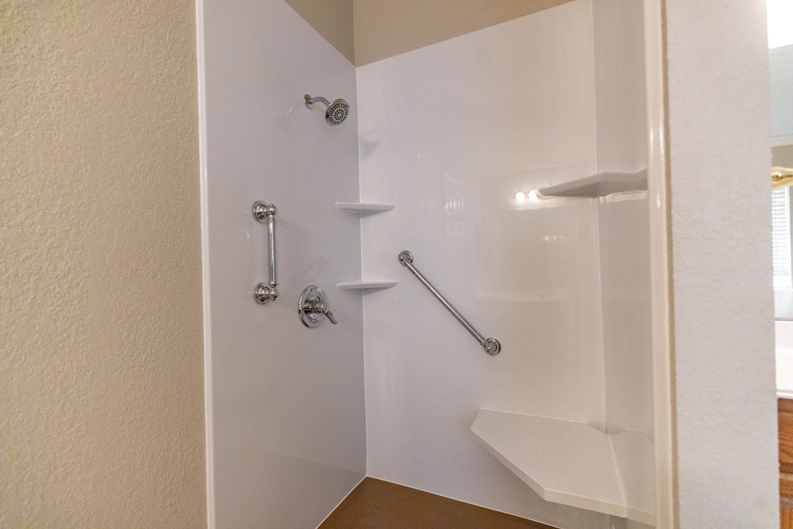 Photo of a new walk in shower with acrylic wall panels. Mid-range walk in shower with a bench seat and grab bars. Walk in shower for seniors