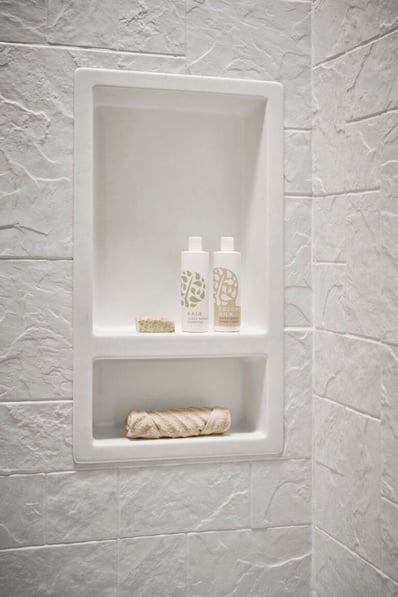 Close up of a walk in shower with textured acrylic walls. The photo shows a shower soap niche with two shelves