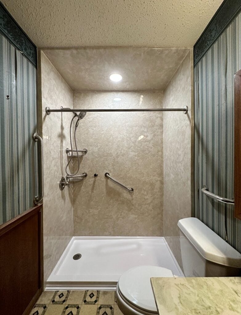 After photo. After a ZINTEX walk in shower replacement. This walk in shower has a low threshold entry, a curtain rod, and multiple grab bars for safe use