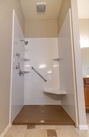 Basic walk in shower stall with acrylic wall panels, a bench seat, and a grab bar