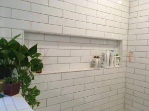 Photo of a built-in storage niche in a shower wall that holds bottles of shampoo, conditioner, and soap
