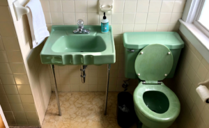 Photo of a vintage bathroom with an outdated green porcelain sink and green porcelain toilet