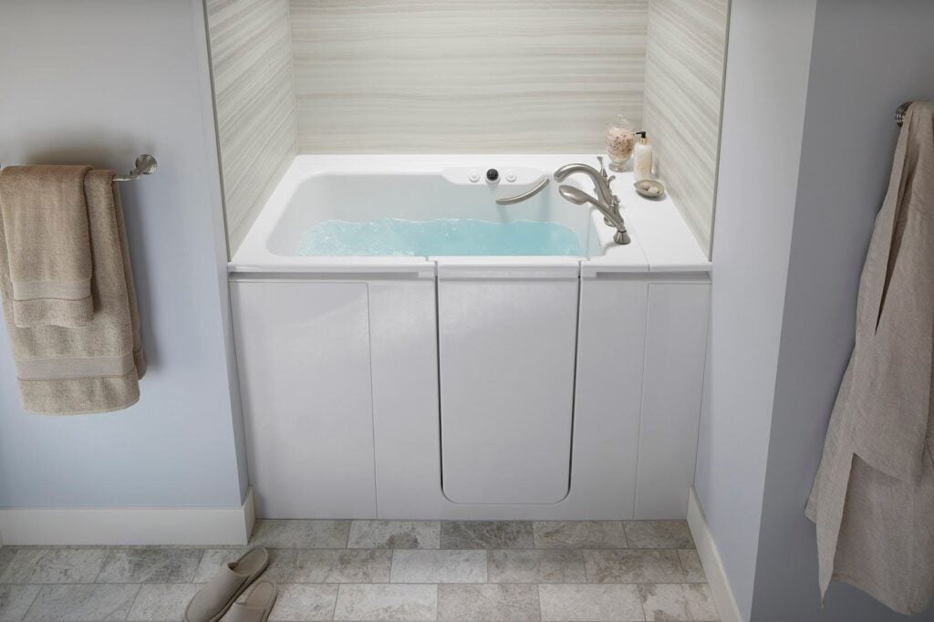 Photo of a walk in tub filled with water. The tub has acrylic shower wall surrounds in a striped pattern