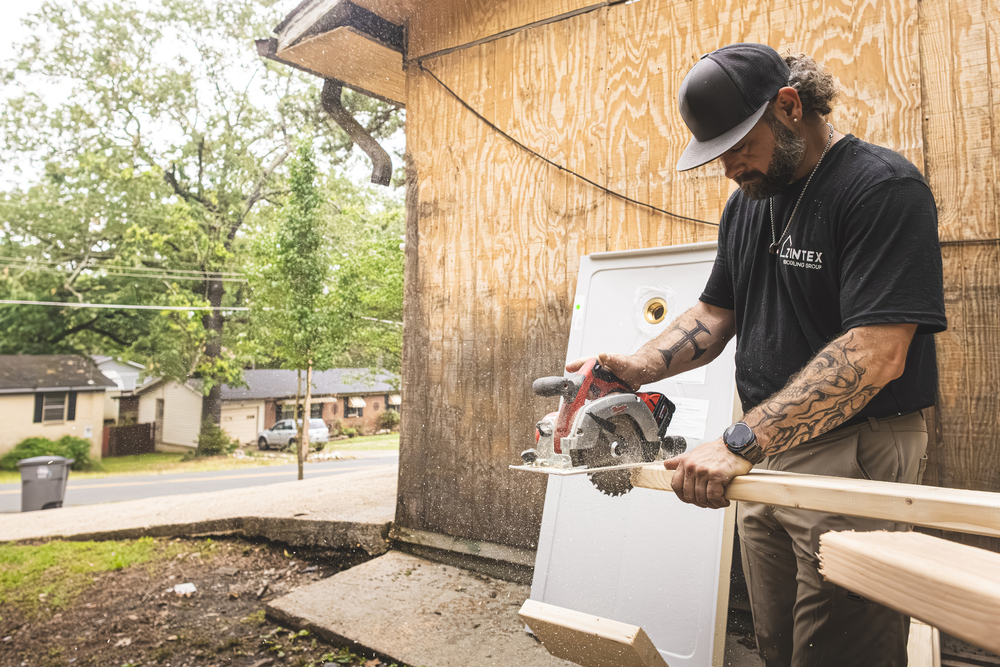 Photo of a zintex installer using a saw blade to cut wood before a new shower install
