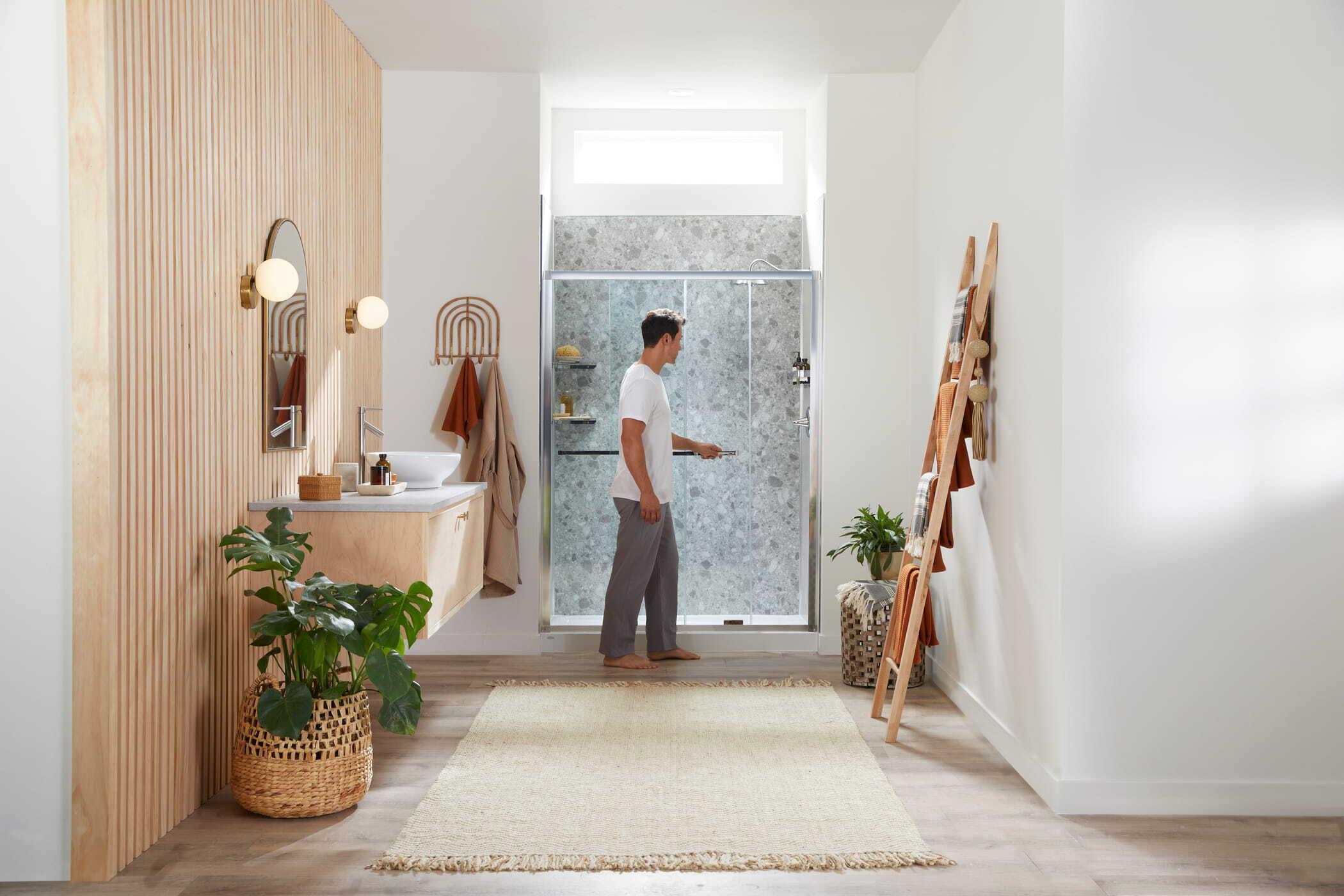 Man opening the glass shower door to his walk in shower with acrylic shower walls