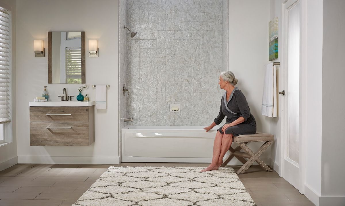 Woman in a bathrobe sitting on a chair next to her Jacuzzi tub shower combo