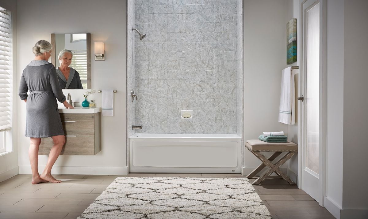 Woman in a bathrobe in front of her vanity mirror next to a Jacuzzi acrylic tub shower combo