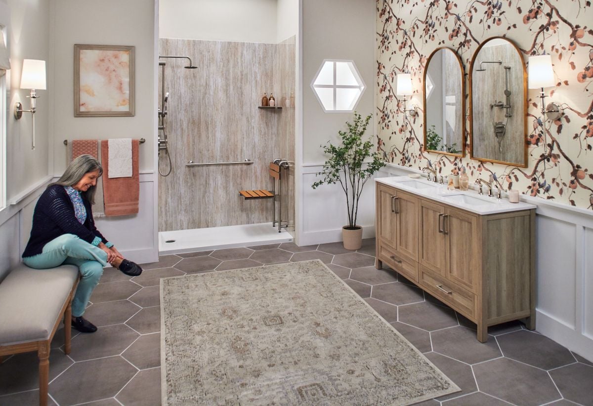 Woman sitting on a bench in her bathroom next to a Jacuzzi walk-in shower with a movable seat