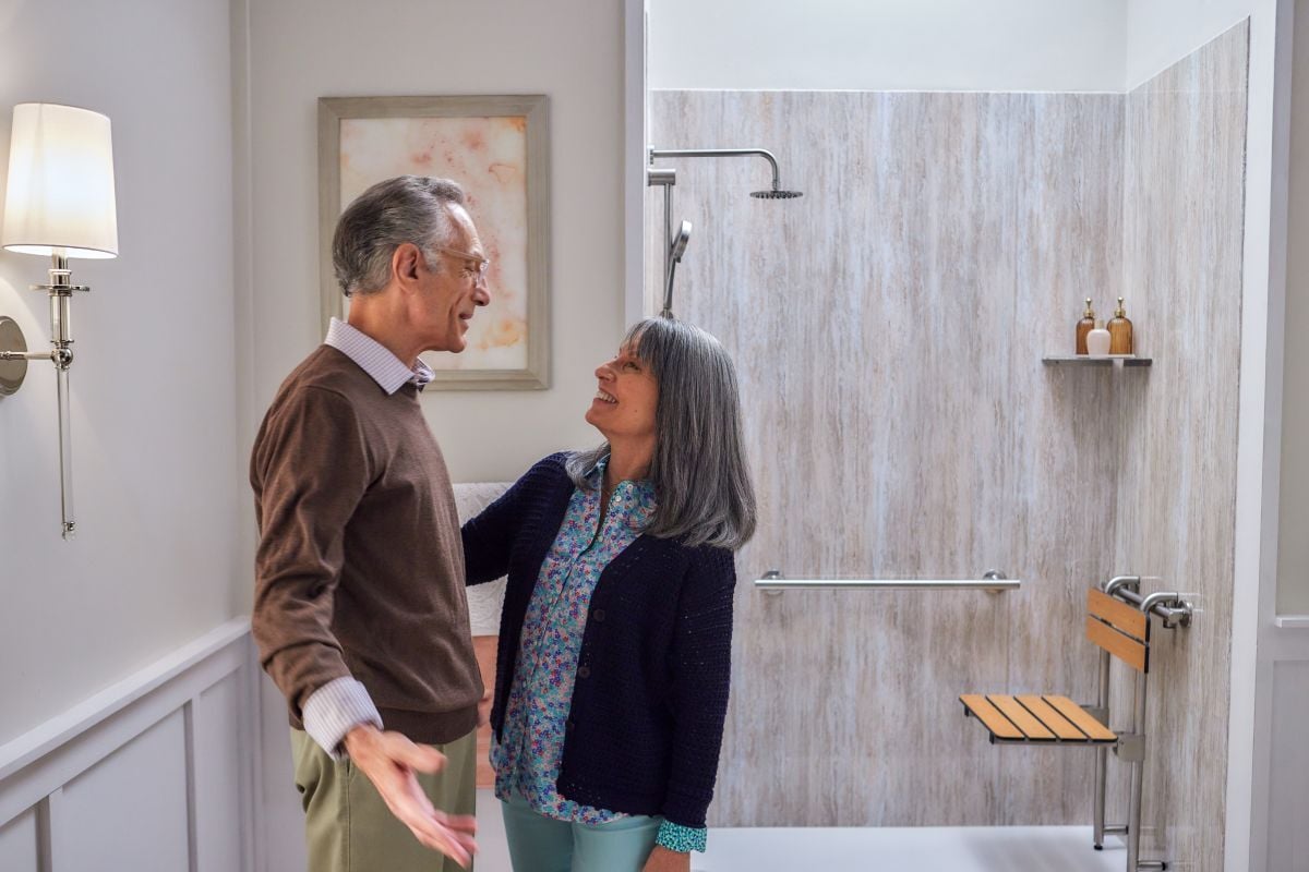 Couple smiling in front of their new accessible Jacuzzi walk in shower with movable hanging seat
