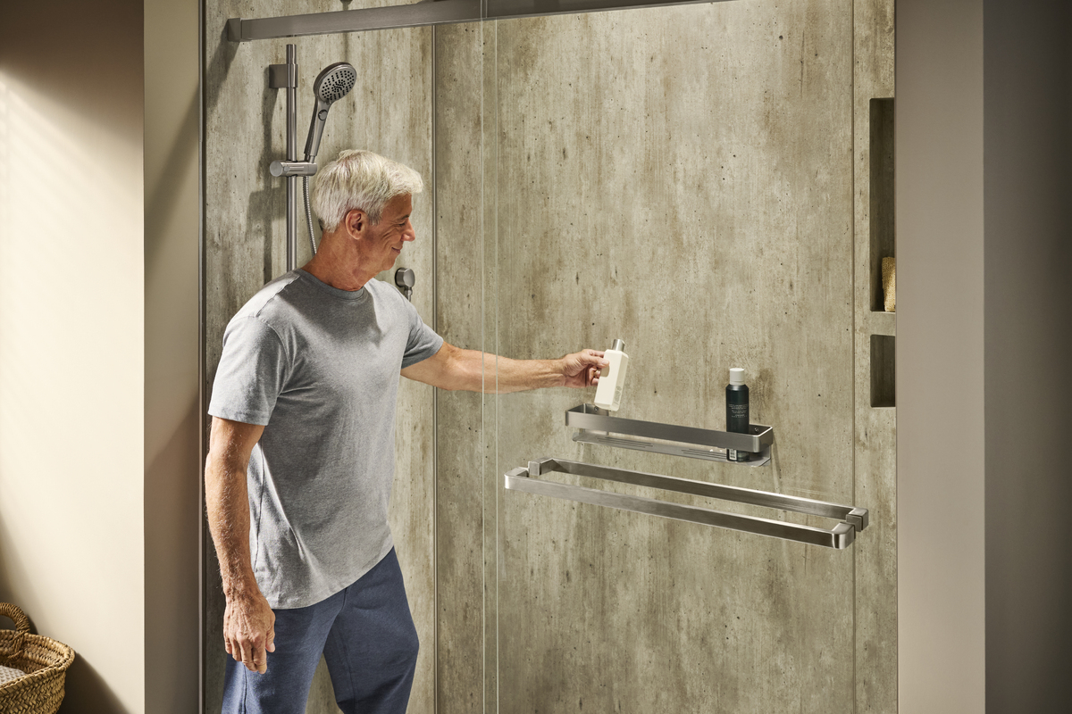 Photo of a man reaching for the sliding glass door of his walk in shower with acrylic walls