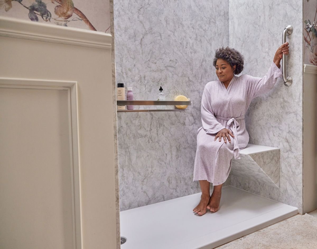 Woman in a robe sitting on her bench seat and holding the grab bar in her Jacuzzi walk-in shower