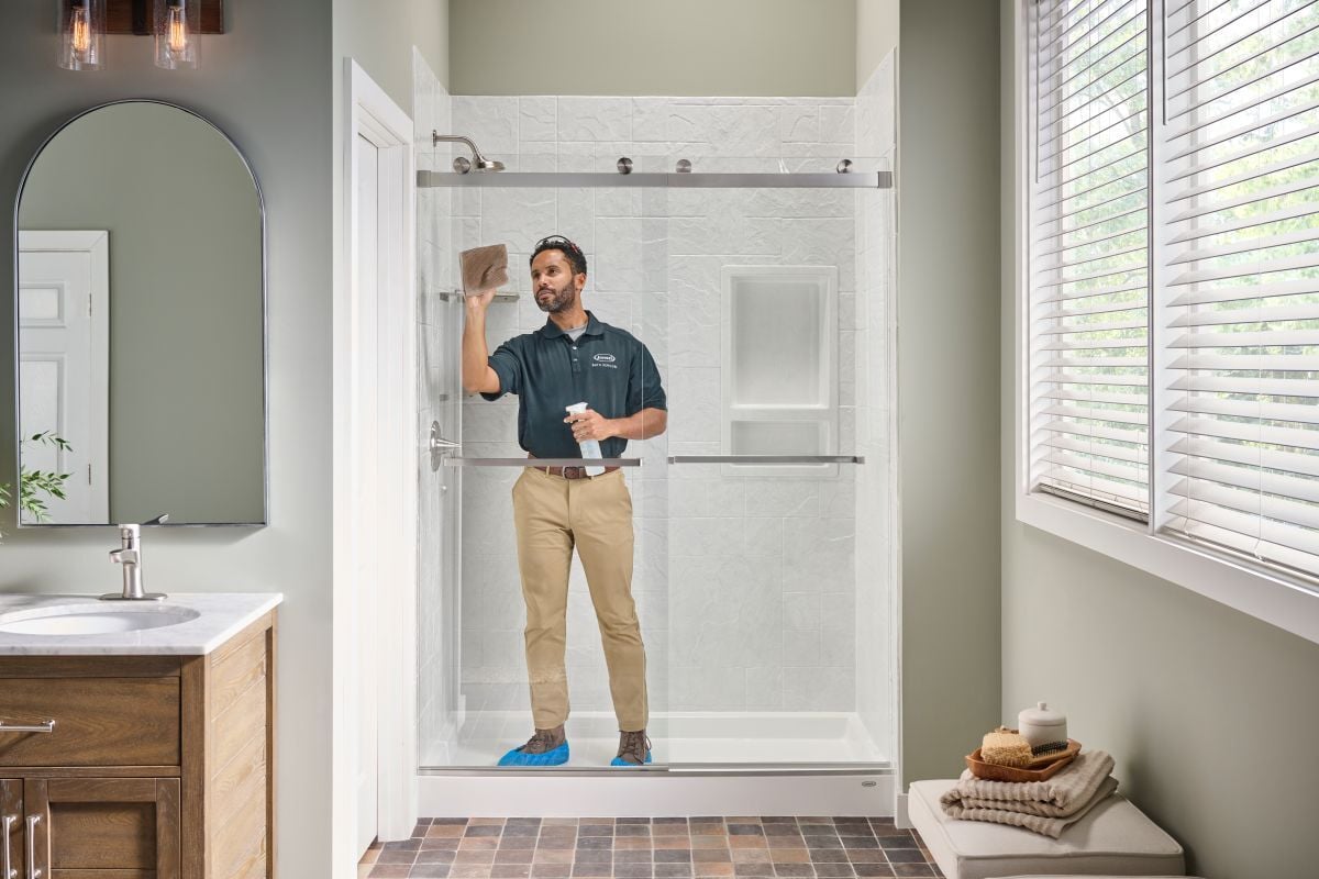 Photo of an installer cleaning the glass of a Jacuzzi walk in shower after completing installation