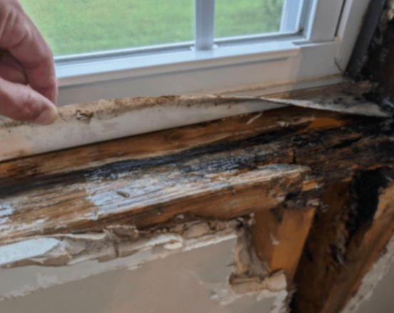 Close up of damage to window frame and wall surrounding an old window before new vinyl window replacement