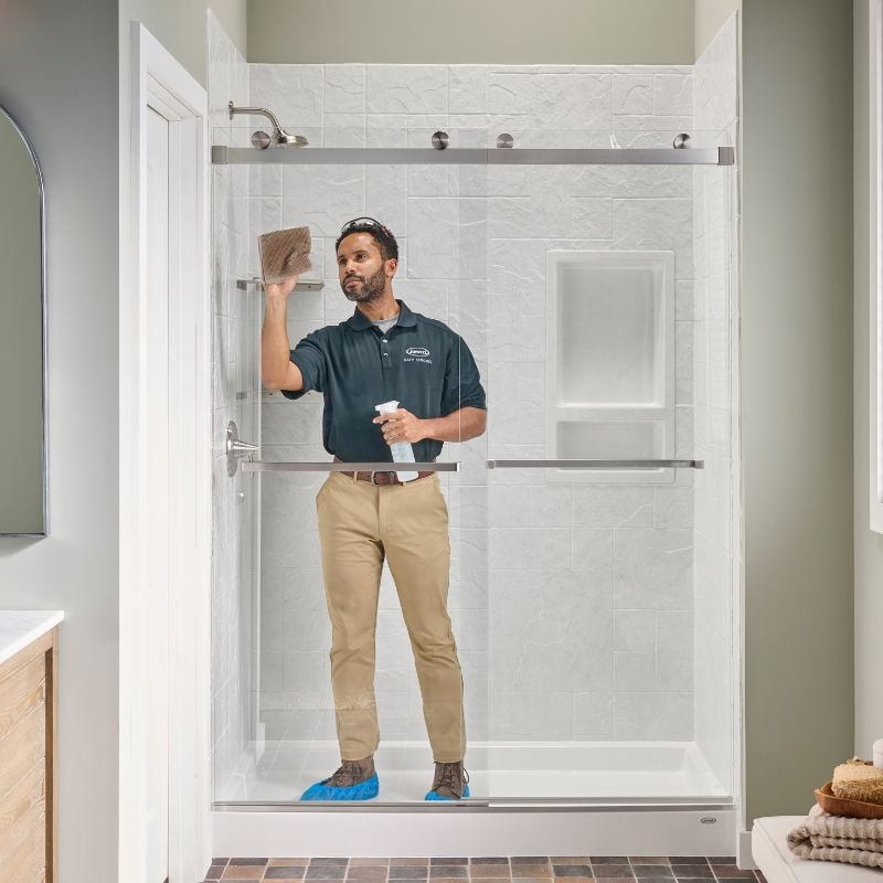Photo of an installer cleaning the sliding glass door after a new walk in shower installation