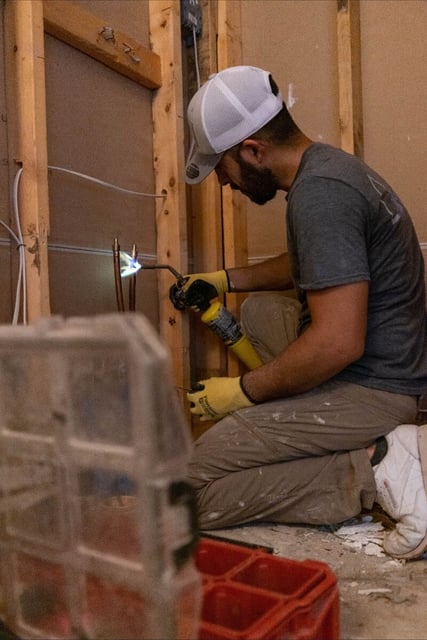 Photo of a ZINTEX installer welding pipes before installing a new walk in shower
